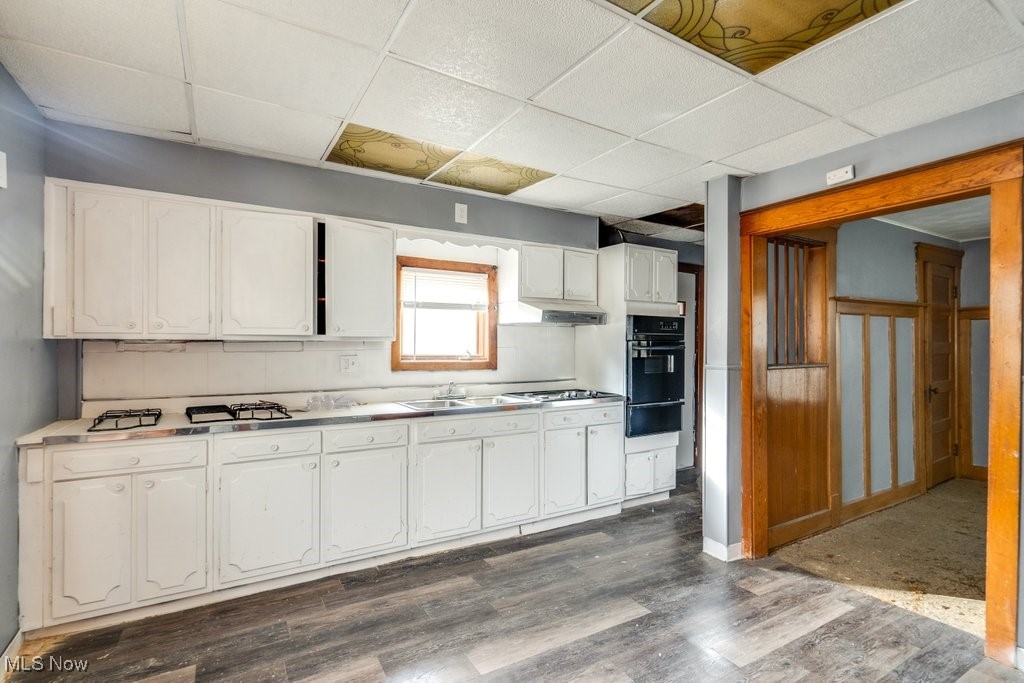 13702 Rugby Road Cleveland, OH 44110 - Photo 5 of 22 Kitchen with black oven, white cabinetry, and dark hardwood / wood-style flooring
