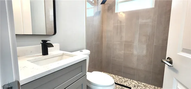 a bathroom with a granite countertop sink toilet and a mirror