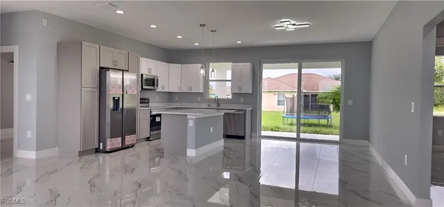 a kitchen with stainless steel appliances granite countertop a refrigerator a sink a stove and white cabinets