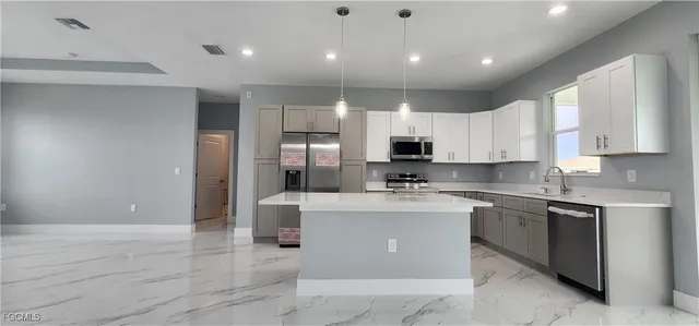 a large kitchen with stainless steel appliances a sink a stove and refrigerator