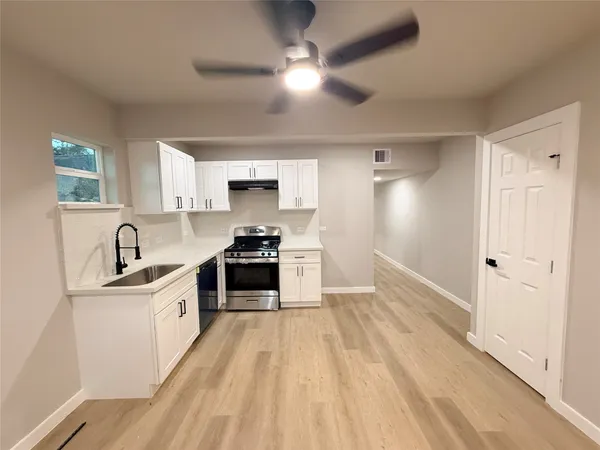 a kitchen with granite countertop a sink cabinets stainless steel appliances and a window