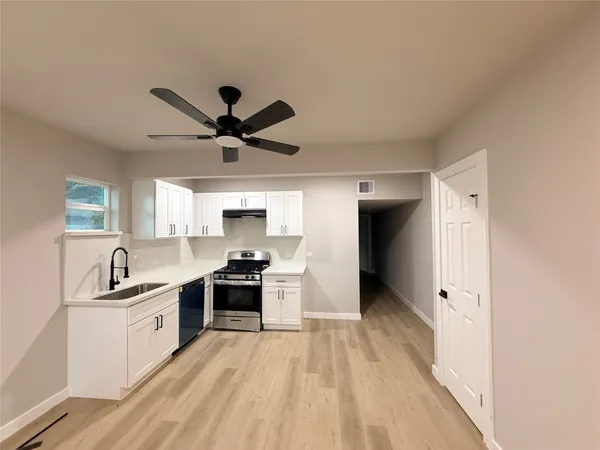 a kitchen with stainless steel appliances a sink a stove a refrigerator cabinets and a window