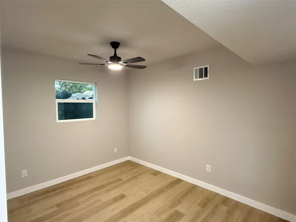 an empty room with a window and a ceiling fan