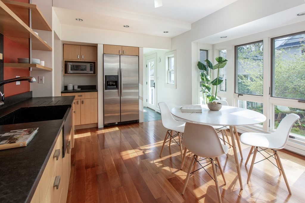 76 Prince Street Boston, MA 02130 - Photo 9 of 23 a kitchen with stainless steel appliances granite countertop a refrigerator a stove top oven and a dining table with wooden floor