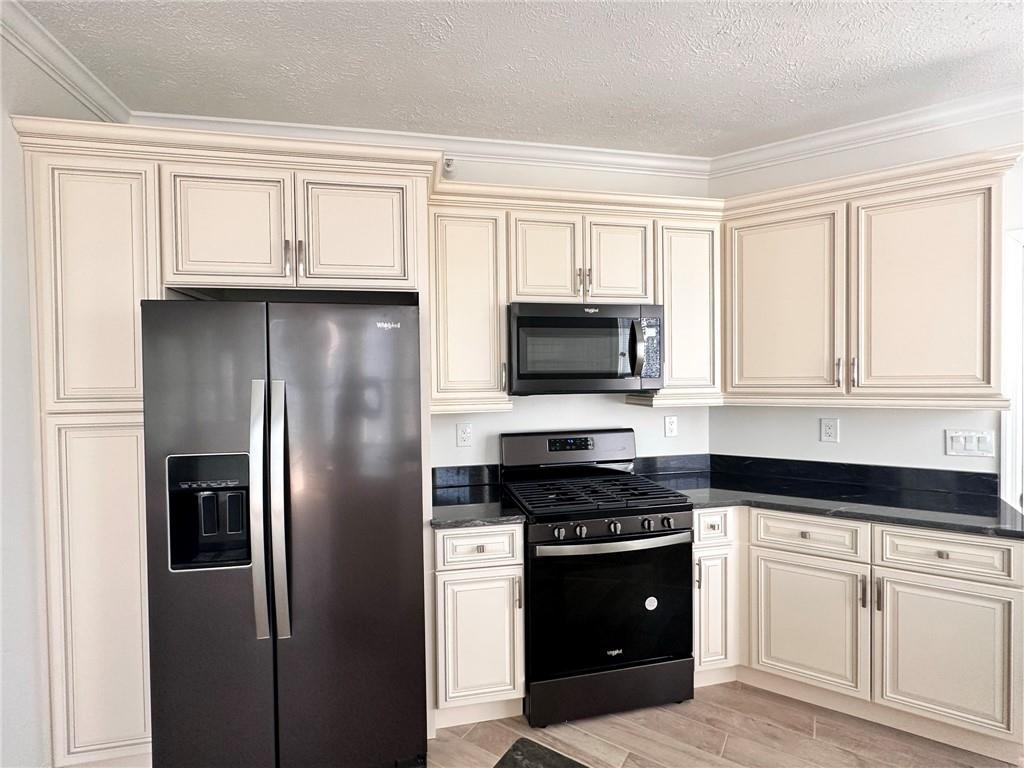 228 Adams Pointe Boulevard, Unit 7 Mars, PA 16046 - Photo 3 of 27 a kitchen with white cabinets and black appliances