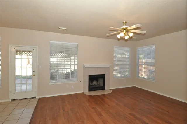 an empty room with windows fireplace and wooden floor