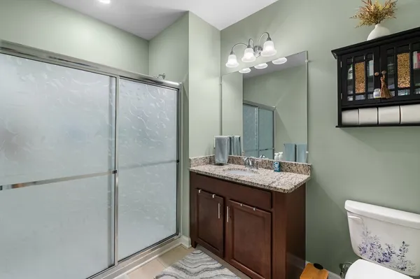 a bathroom with a granite countertop sink a toilet a large mirror and shower