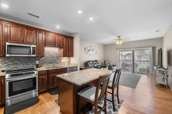 a kitchen with granite countertop kitchen island wooden cabinets and stainless steel appliances