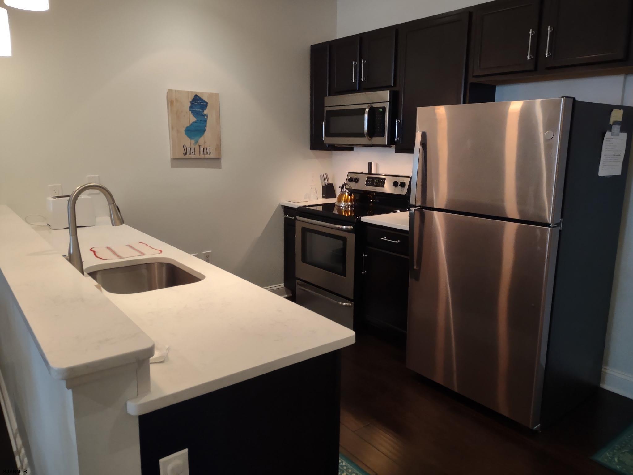 810 Asbury Avenue, Unit 303 Ocean City, NJ 08226 - Photo 3 of 20 a kitchen with stainless steel appliances a refrigerator sink and microwave