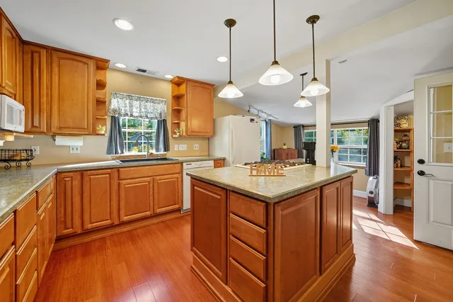a kitchen with a stove a sink a center island and wooden floor