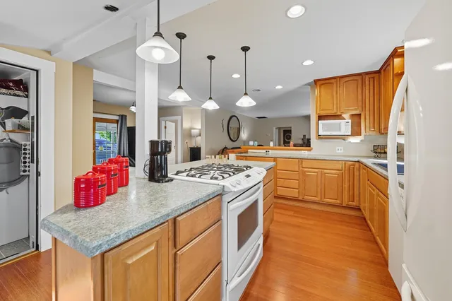 a kitchen with kitchen island granite countertop a stove a sink a refrigerator and a dining table