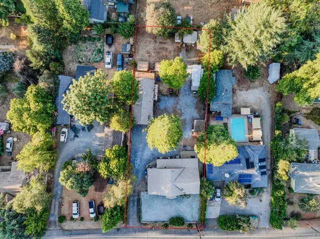 an aerial view of a house with a yard and large trees