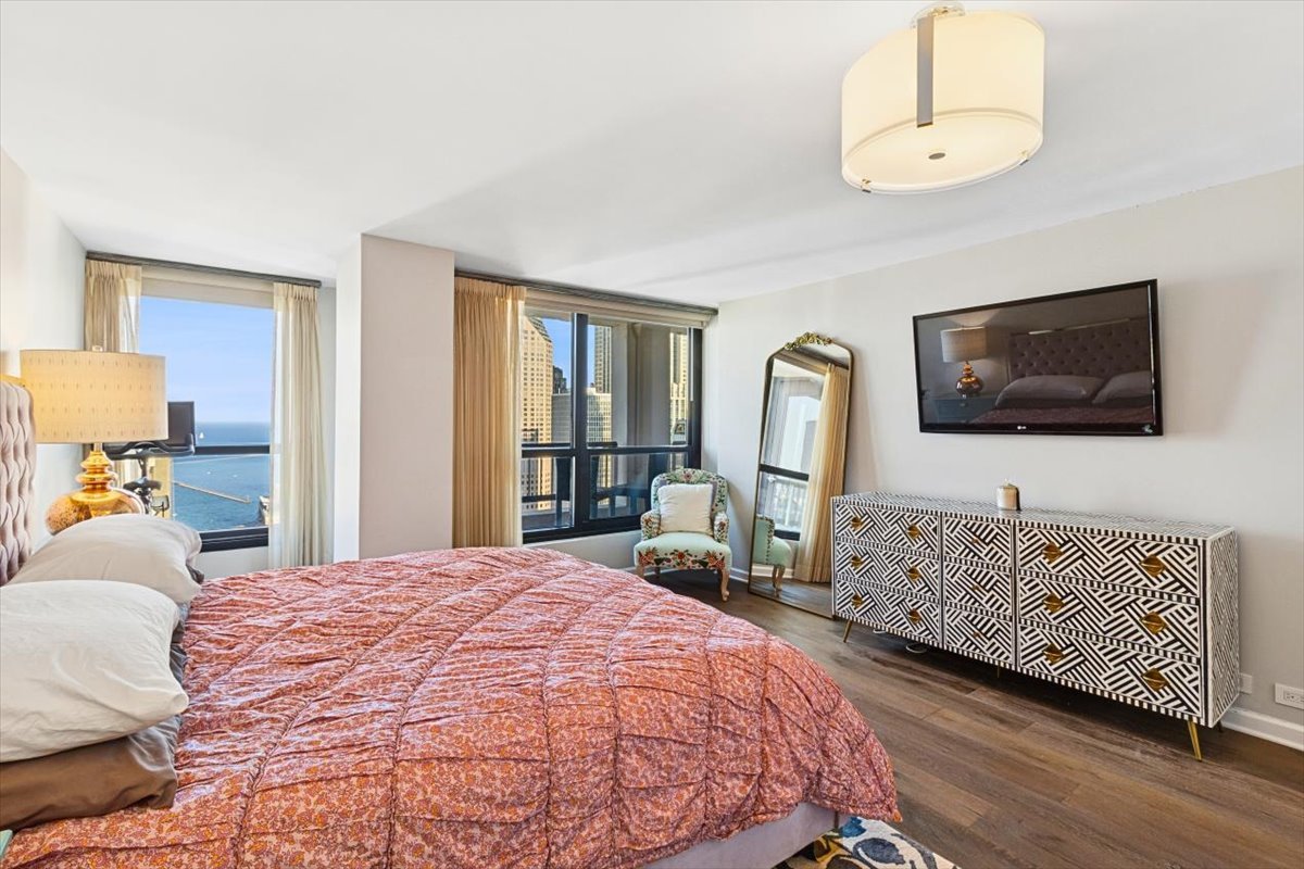 1030 North State Street, Unit 33GH Chicago, IL 60610 - Photo 13 of 26 a bedroom with a bed a mirror on dresser and a flat screen tv