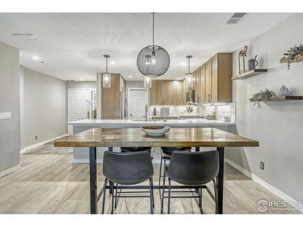 a dining hall with stainless steel appliances kitchen island a table and chairs