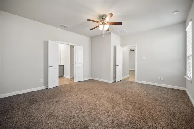 an empty room with windows and fan