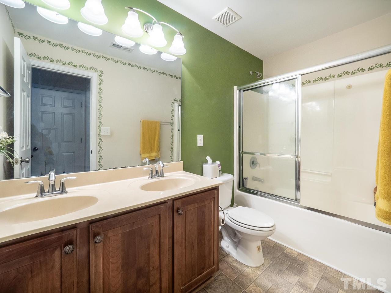 3016 Red Grape Drive Raleigh, NC 27607 - Photo 16 of 23 a bathroom with a granite countertop sink toilet a mirror a vanity and shower