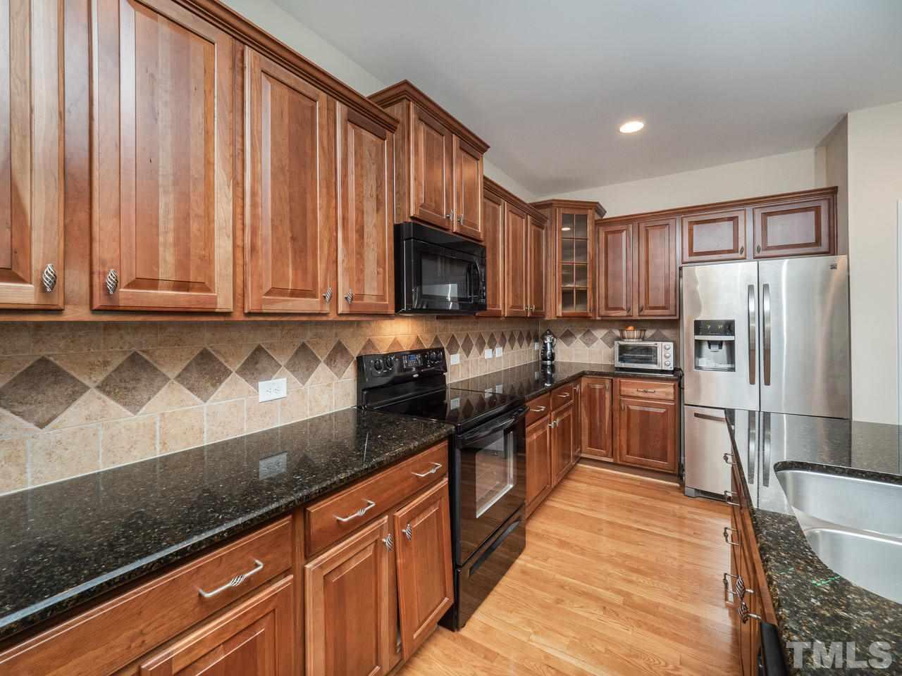 3016 Red Grape Drive Raleigh, NC 27607 - Photo 10 of 23 a kitchen with granite countertop wooden cabinets a refrigerator and a sink