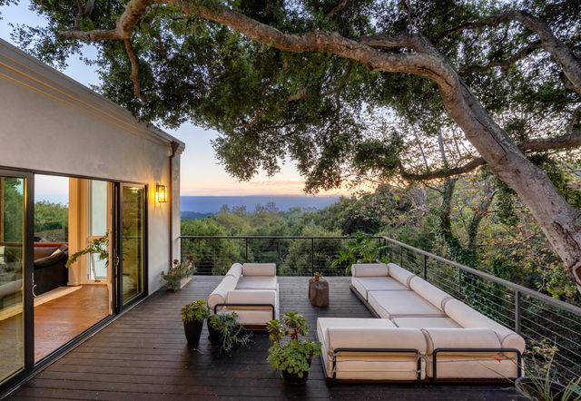 a view of a patio with couches table and chairs with wooden floor and fence