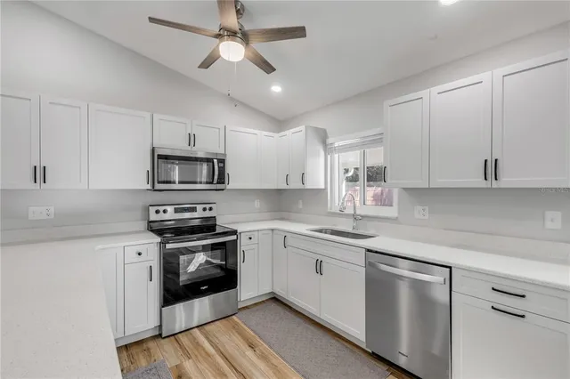 a kitchen with stainless steel appliances granite countertop a sink a stove top oven and white cabinets