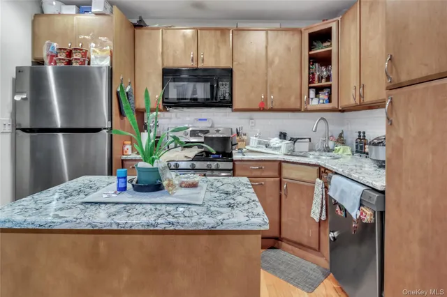 a living room with stainless steel appliances granite countertop a kitchen island a stove and a sink