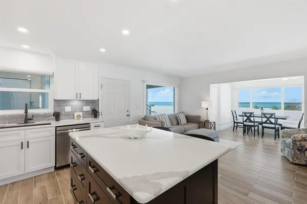 a kitchen with a stove a sink dishwasher a dining table and chairs with wooden floor