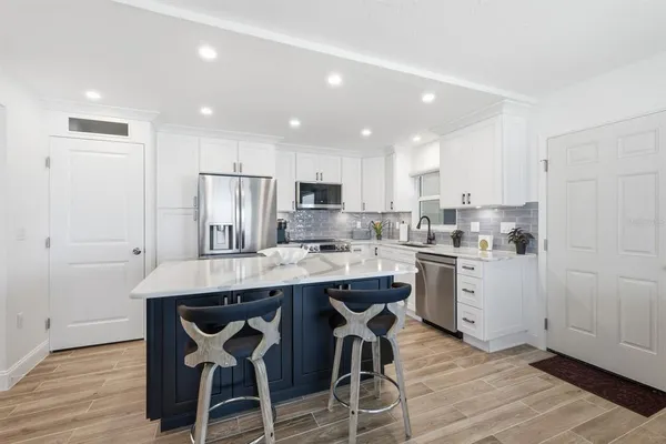 a kitchen with a sink a refrigerator and white cabinets with wooden floor