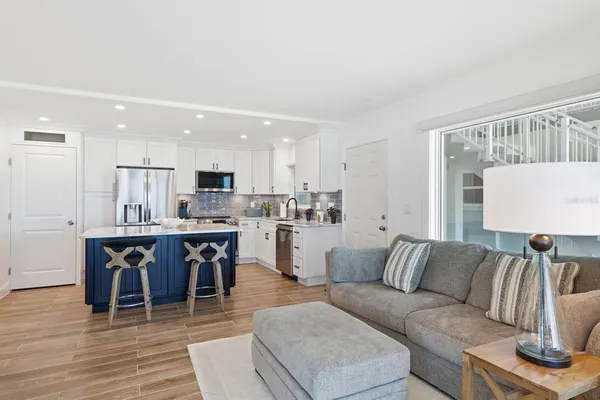 a living room kitchen with a dining table wooden floor and a view of kitchen
