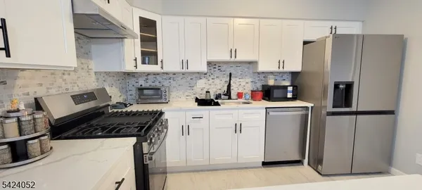a kitchen with refrigerator a stove and white cabinets