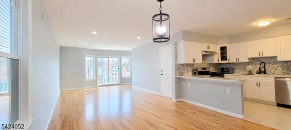 a kitchen with stainless steel appliances granite countertop a refrigerator a stove a microwave oven a sink dishwasher and white cabinets with wooden floor