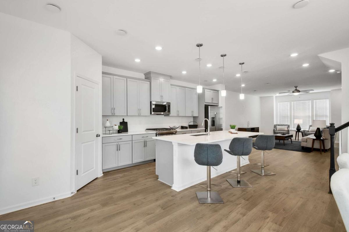 1526 Halstead Place, Unit 1526 Suwanee, GA 30024 - Photo 4 of 24 a kitchen with a sink and chairs