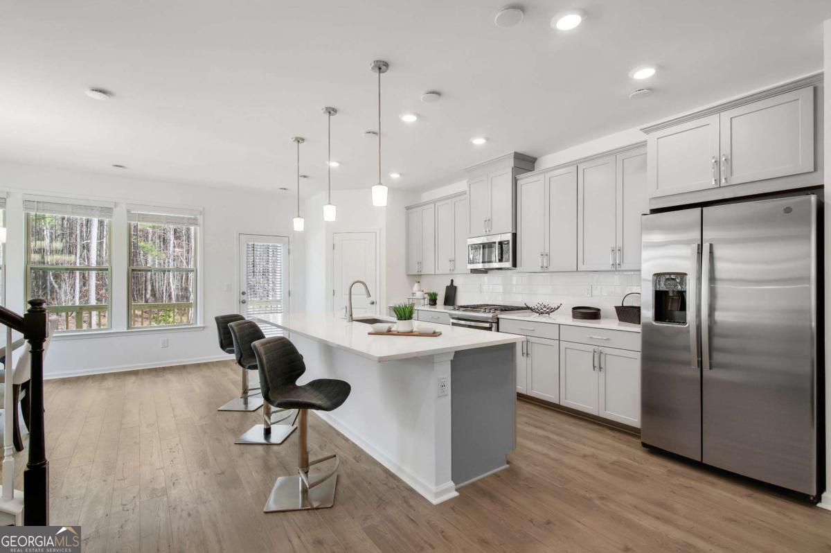 1526 Halstead Place, Unit 1526 Suwanee, GA 30024 - Photo 6 of 24 a kitchen with kitchen island a white cabinets and refrigerator