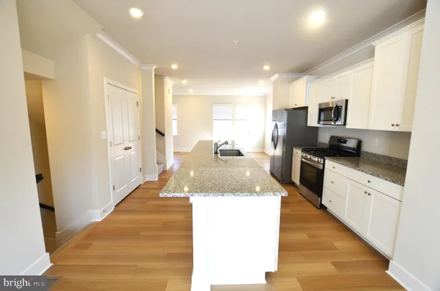 a large kitchen with stainless steel appliances kitchen island granite countertop a refrigerator and a sink