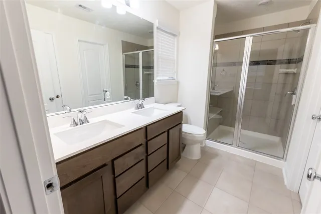 a bathroom with a double vanity sink toilet mirror and shower