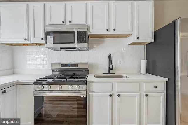 a kitchen with stainless steel appliances granite countertop white cabinets and a stove a oven with white countertops