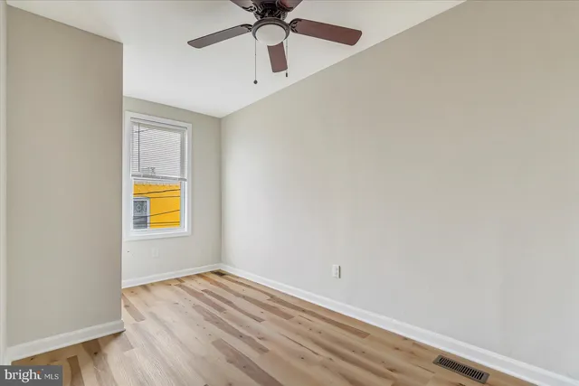 an empty room with a window and ceiling fan