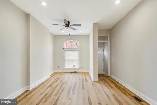 a view of empty room with wooden floor and fan