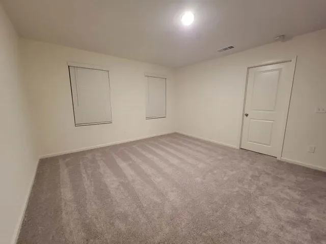 a view of an empty room and chandelier fan