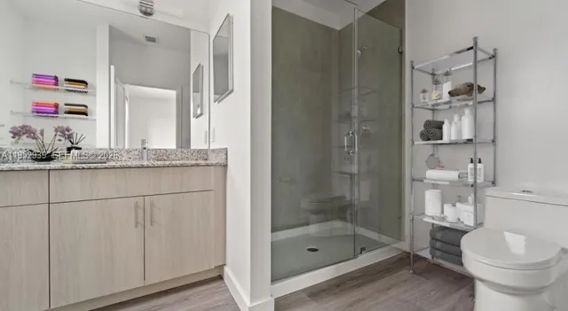 a bathroom with a granite countertop sink a toilet and shower