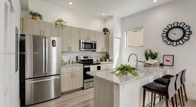 a kitchen with stainless steel appliances granite countertop a refrigerator a stove a sink dishwasher a dining table and chairs with wooden floor