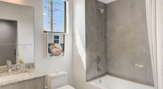 a bathroom with a granite countertop sink a toilet and shower