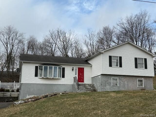 Split level home with a front lawn and fence