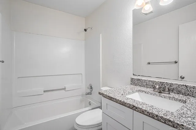 a bathroom with a granite countertop sink a toilet and shower
