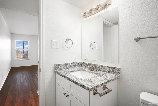 a bathroom with a granite countertop sink a mirror and shower