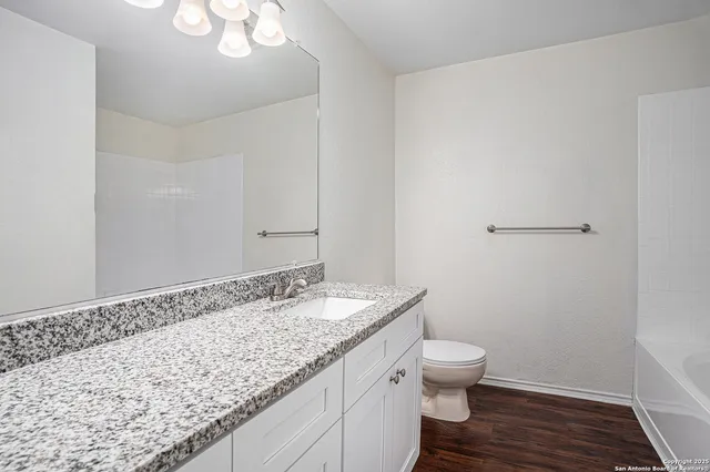 a bathroom with a granite countertop sink a toilet and a mirror