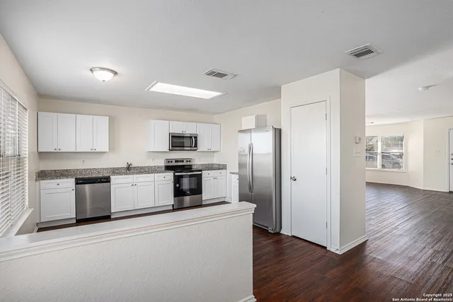 a kitchen with granite countertop a refrigerator and a stove top oven