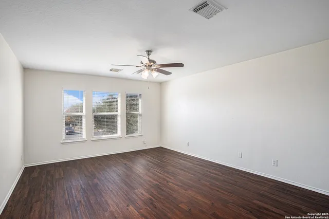 an empty room with wooden floor and windows