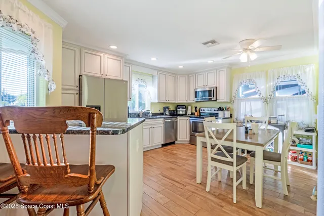 a kitchen with stainless steel appliances granite countertop a table chairs and a refrigerator