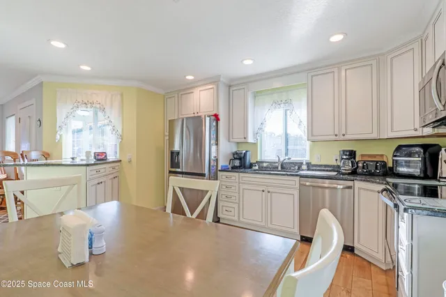 a kitchen with stainless steel appliances granite countertop a stove a sink a refrigerator white cabinets and wooden floor