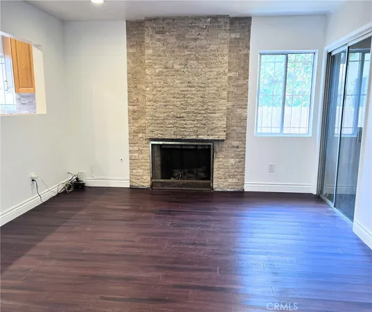 an empty room with wooden floor fireplace and windows