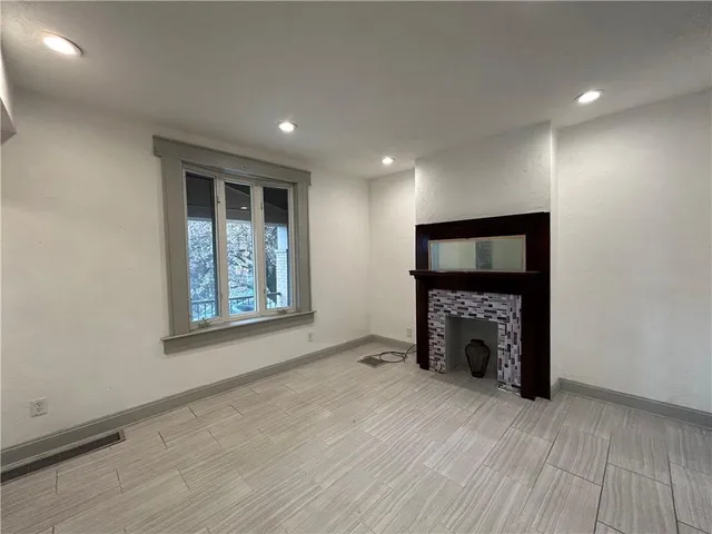 an empty room with windows fireplace and wooden floor